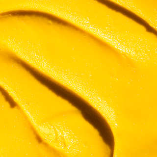 Close-up of unctuous mango-hued gelato, rippled and glossy in the sunshine.